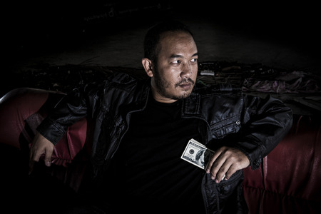 The image of a man who looks like a mafia, drug dealers who have money in hand.の写真素材