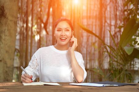 Women with mobile phones and tablets in the beautiful backyard.の写真素材