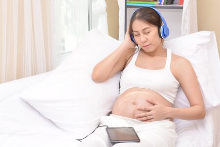 Pregnant women are listening to music through headphones.の写真素材