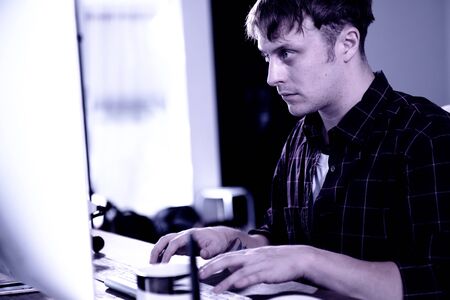 A young man working on a computer in their home.