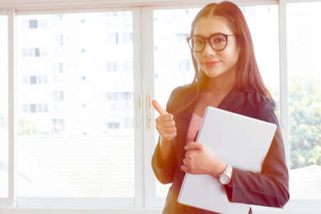 Young business woman holding a computer standing with confident.の写真素材