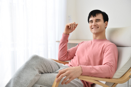 Portrait of young man indoors with very handsome face in pink casual shirt on bedroomの写真素材