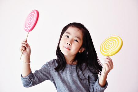Little girl is enjoying candy. Parents just need to be careful about oral health.の写真素材