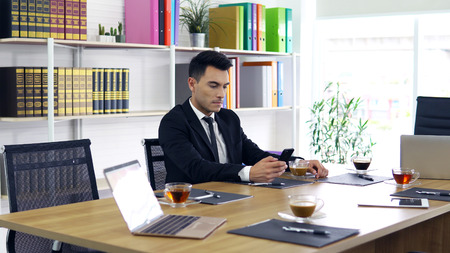 Businessman are checking information through smartphones. Waiting for the meetingの写真素材