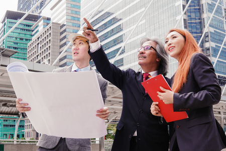 Executives, enjineer and secretaries are discussing and viewing the plan at the construction site.の写真素材