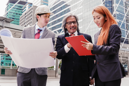 Executives, enjineer and secretaries are discussing and viewing the plan at the construction site.の写真素材