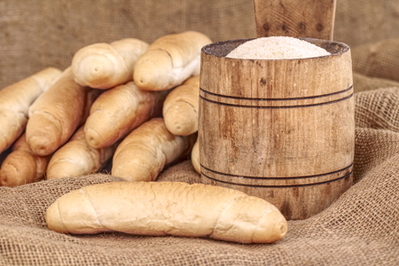 Vintage small wooden bucket with breadcrumbs and blurry bread rolls in the backgroundの写真素材