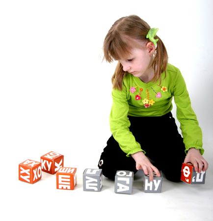 little girl in green shirt playing with letter bricksの写真素材