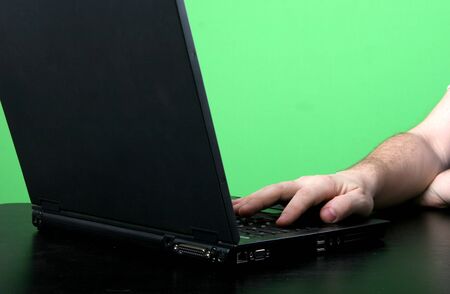 two man's hands lay down the keyboard of the deep grey laptop with green background