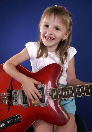 little girl playing with red electric guitar and singingの写真素材
