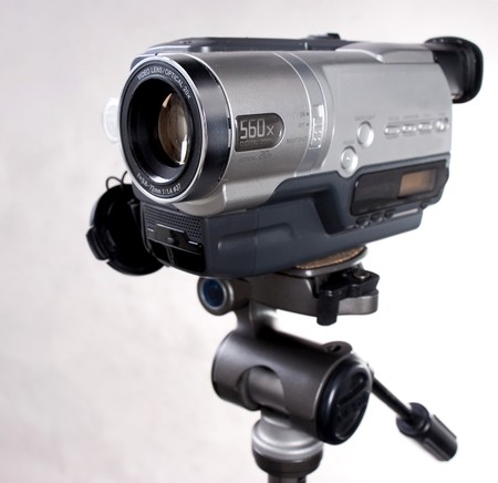 grey home video camera on tripod with grey background