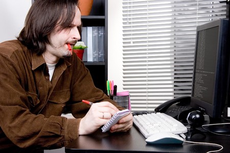 man write information to notepad near the computerの写真素材