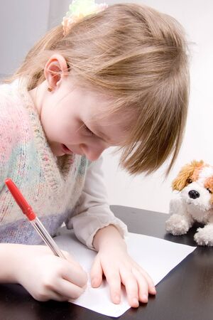 the little girl drawing with red pen at white paperの写真素材