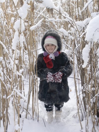 little girl in fur stay in show bush like small hearの写真素材