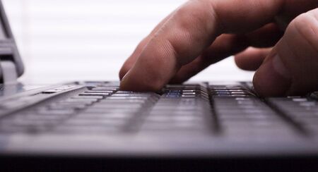 close-up hand typing on black laptop keyboard