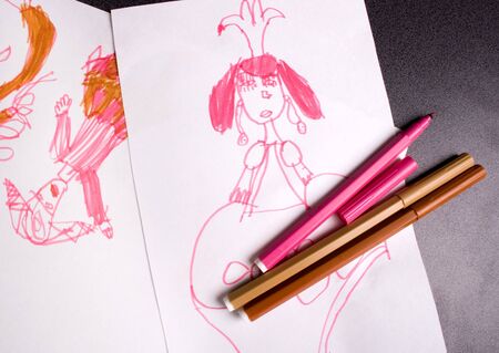 childish drawing and some markers laying down the tableの写真素材