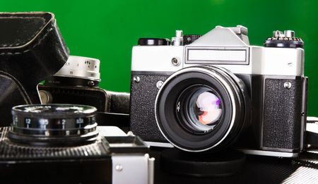 the three old photo cameras at green backgroundの写真素材