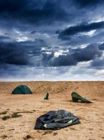 blue broken camping tent on the beach at the stormy weather and good tent at backの写真素材