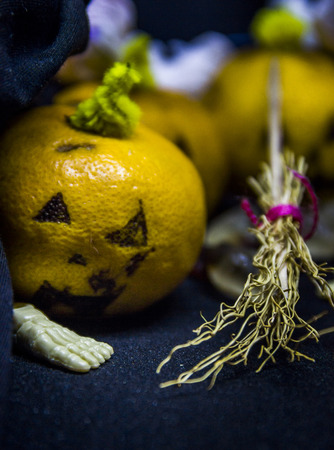 a halloween still life with tangerine and apple as pumpkins and handmade witch broomの写真素材