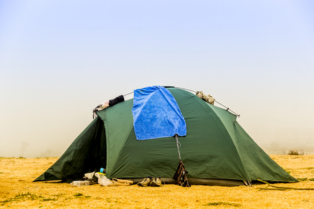 green tourist tent on the sea beach at foggy weatherの写真素材
