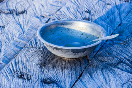 close-up of a metal plate and spoon with morning frost on wooden tableの写真素材