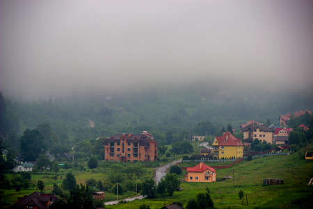some cottages and unfinished houses in the valley near the spruse forest in Carpathians at foggy...