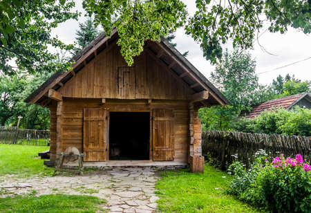 vintage rural barn with grinding wheel on farmyard in reconstruction of ukrainian village of 19th century as part of Ivan Franko Literary Memorial Museum in Nahuievychi, Lviv region of Ukraineのeditorial素材