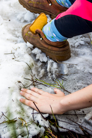 close-up of a female hand and legs leather boots on the snowy peak of mountainの写真素材