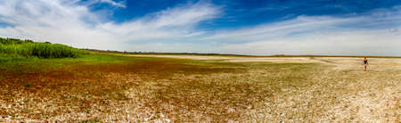 a panoramic view of a dried lake with walking woman on steppe near the Sea of Azov, Ukraineの写真素材