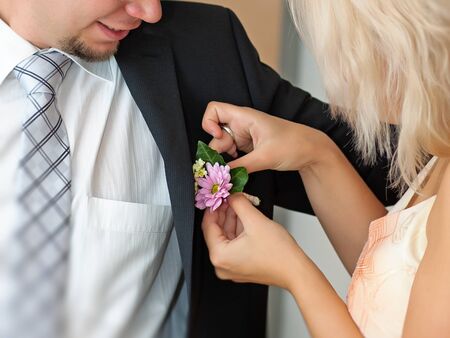 Bride adjusting beautiful groom's boutonniereの写真素材