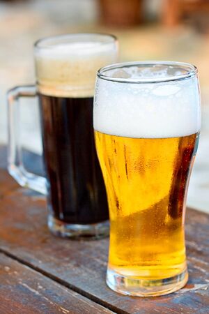 Glass dark and light of beer on wood tableの写真素材