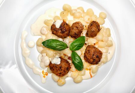 Gnocchi with cheese sauce and meatballs and decorated with fresh basil leavesの写真素材