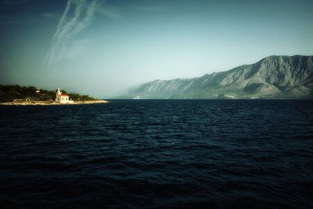 Chapel by the sea in dark colored shade - a view from the seaの写真素材