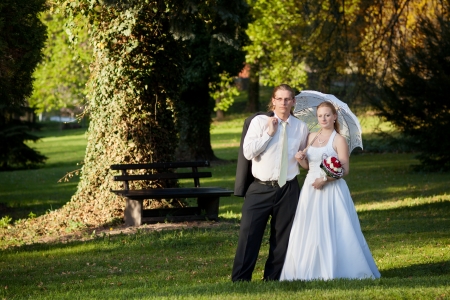 newlyweds in the park with umbrellaの写真素材