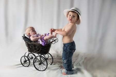 Portrait of a brother and sister lying in a strollerの写真素材