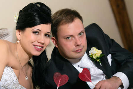 Portrait of newlyweds holding a sweet lollipop in the shape of heartの写真素材