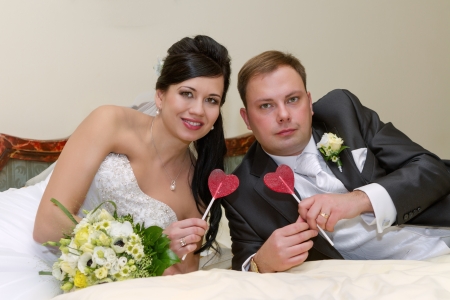 Portrait of newlyweds holding a sweet lollipop in the shape of heartの写真素材