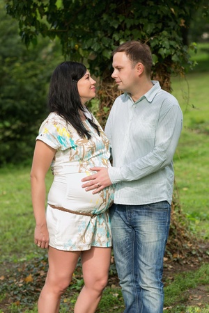Happy pregnant woman and her husband in the park の写真素材
