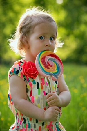 Little girl licking a lollipop on a summer dayの写真素材