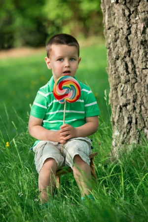Portrait of beautiful joyful little boy with lollipop  Outdoors の写真素材