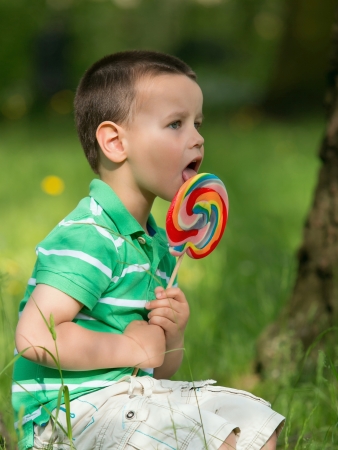 Portrait of beautiful joyful little boy with lollipop  Outdoors の写真素材