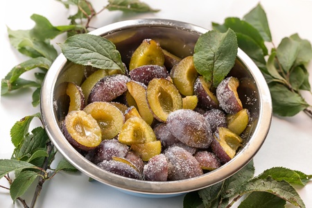 Bowl halved plums sprinkled with sugar on white backgroundの写真素材