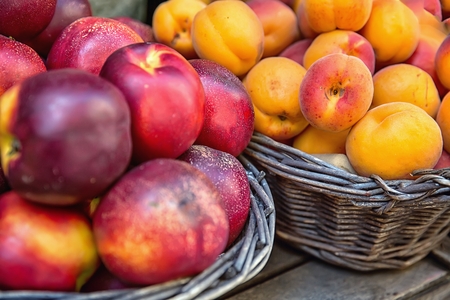 Nectarines and apricots in wicker baskets at the marketの写真素材