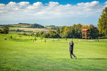 Pretty young lady golfer view from below against a blue skyの写真素材