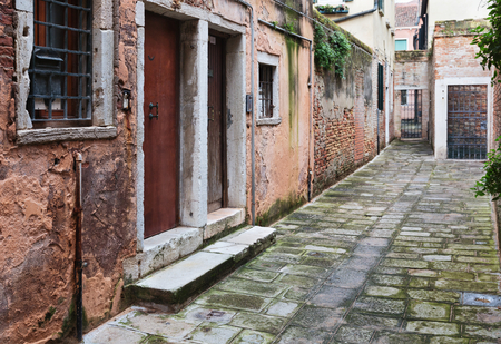 Narrow street among old colorful brick houses in Venice, Italy の写真素材