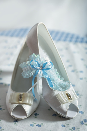 Bride shoes garter, with blue ribbon, and blue background. Closeup of wedding accessories.の写真素材