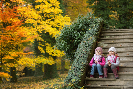 Children sitting on old stone stairs in the parkの写真素材