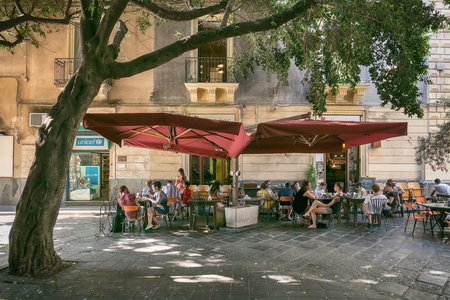 Catania, Sicily, ITALY - JUNE 25 2016 People sitting on the street in the shade under a large tree at the outdoor restaurantのeditorial素材