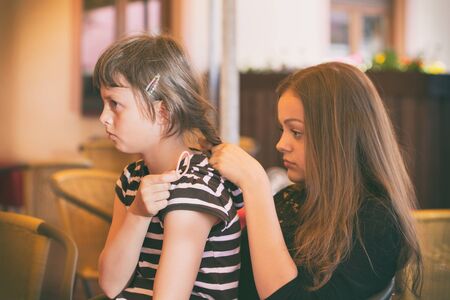 Two young girls while combing hairの写真素材
