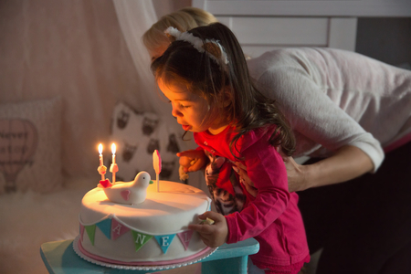 Little girl celebrating her second birthday and blowing on candles for his birthday cakeの写真素材